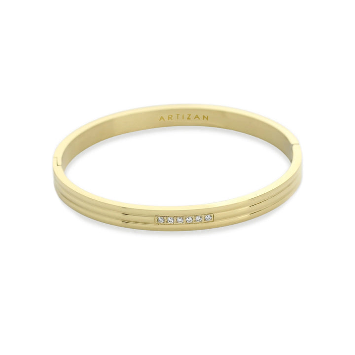 The MIDDLE LANE BANGLE, which is a single sleek gold bracelet, features a modern design with a delicate row of five sparkling cubic zirconia stones embedded at the center. This minimalistic yet elegant bangle is perfect for adding a touch of sophistication to everyday wear or special occasions.