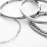 The Chain Silver Bracelet Stack, a four-piece set of silver bracelets including a chunky chain bracelet, a bangle with cubic zirconia accents, a simple bangle, and a delicate chain with cubic zirconia accents.