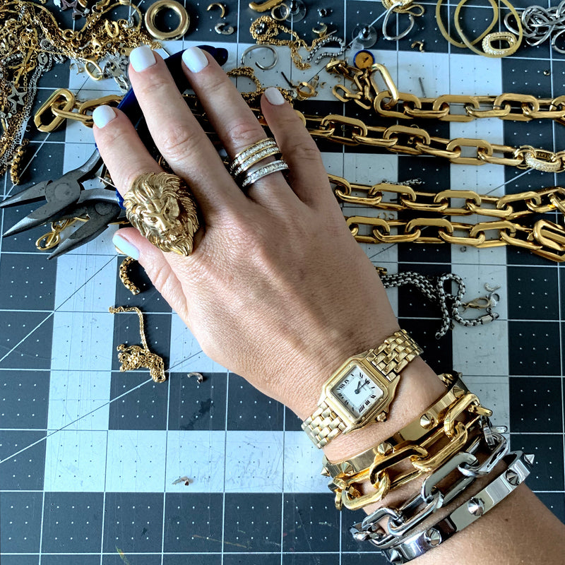 Model wearing the Lion Ring and SQUARE ZIRCONIA DOBLE in Silver and Gold. She is also wearing a gold watch, two PUERTO CHAIN BRACELET in Stainless Steel Rhodium Plated and Gold Plated Chains, Crystal bangle in Silver and Spike bangle in Silver.