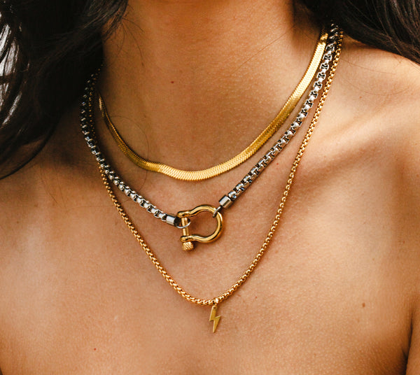 Model wearing 3 Chains Layered Set THE HERRADURA & THE SNAKE which comes with gold flat chain, Silver chain with gold herradura clasp and a gold plated long chain with a gold plated lightning bolt pendant.