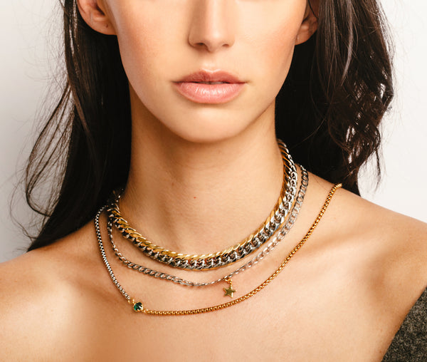 Model wearing the 3 piece Emerald and Mix set which comes with a half gold and half silver thin chain with green emerald stone in the center, silver chain with star pendant, and chunky Mix chain which is a mix of gold and silver. 