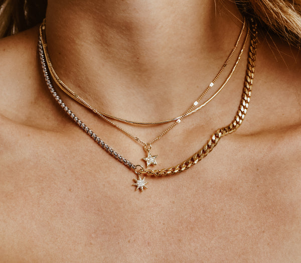 Model wearing the UP HIGH NECKLACE SET which comes with three necklaces made of 18k Gold plated Stainless steel chain. One is a thin gold necklace with a star zirconia pendant, gold plain chain and half silver and gold chain with a sunburst zirconia pendant.