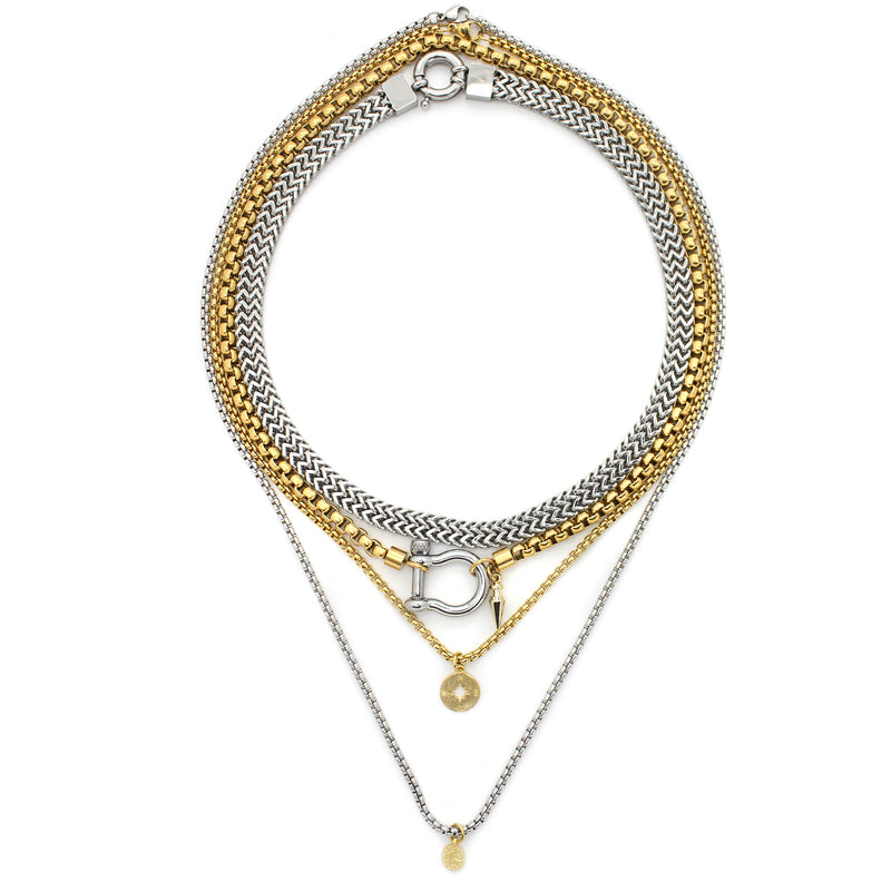 The HERRADURA LAYERED NECKLACE SET in silver variant which includes 4 separate chains. It includes the Marinero silver chain, 18k gold plated stainless steel chain with an silver horseshoe clasp and gold plated spike pendant. The other two necklaces are the gold plated chain with the gold compass disc and silver chain with gold ottoman disc pendants.