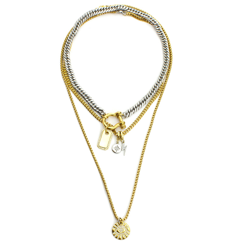 The HERRADURA SHINES which includes 3 separate chains. Two 18k gold plated stainless steel chains with a Mini lightning, Northstar and Evil eye zirconia charms. The shortest necklace is a stainless steel chunky chain with an 18k gold plated horseshoe clasp and 18k gold plated brass board with zirconia.