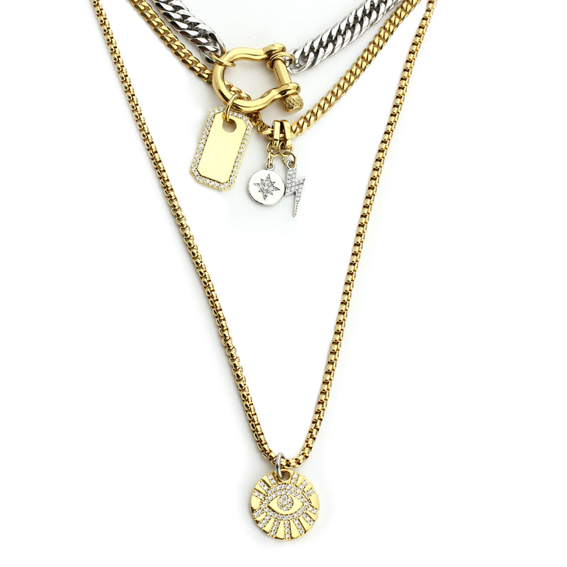 The HERRADURA SHINES which includes 3 separate chains. Two 18k gold plated stainless steel chains with a Mini lightning, Northstar and Evil eye zirconia charms. The shortest necklace is a stainless steel chunky chain with an 18k gold plated horseshoe clasp and 18k gold plated brass board with zirconia.