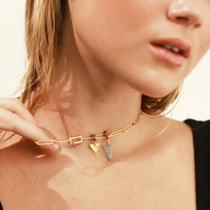 Model wearing the Paper clip necklace with the spike diamond filled charm and the Triangle Link Charm, a gold charm with a minimalist triangle design and a single cubic zirconia stone.