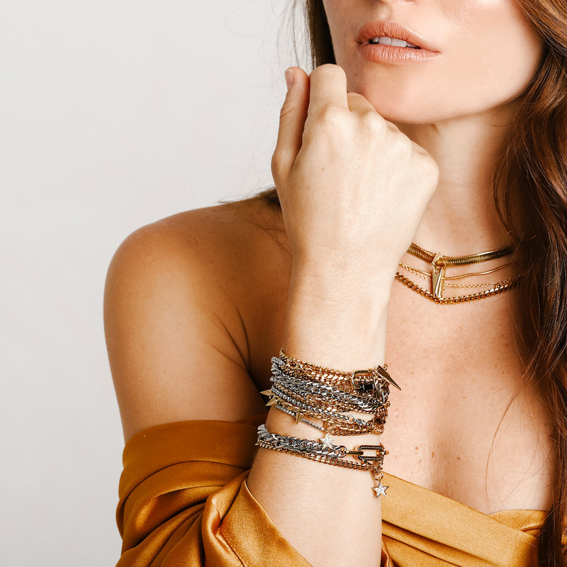 Model wearing the WILD LAYERED NECKLACE SET which includes 4 gold separate chains and stack of bracelet chains which include the La Rosa bracelet, Iron bracelet, Ischia Bracelet in silver and gold, Espresso Blended, Orzo blended and the Shakerato Blended Bracelet.