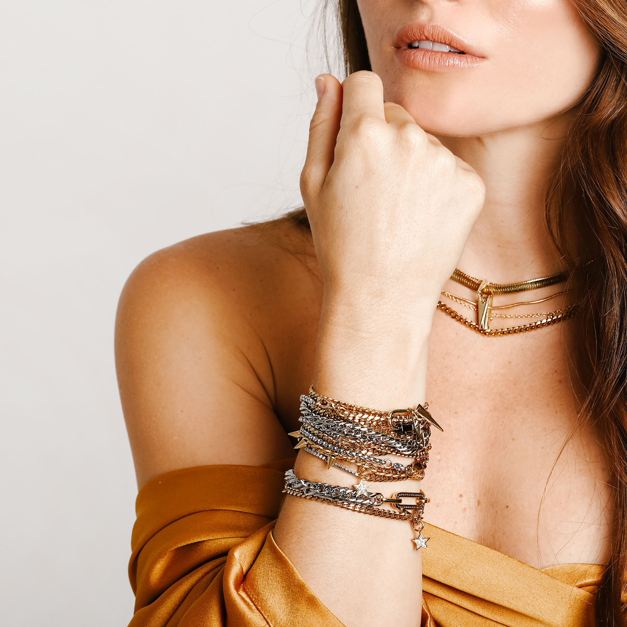 Model wearing the WILD LAYERED NECKLACE SET which includes 4 gold separate chains and stack of bracelet chains which include the La Rosa bracelet, Iron bracelet, Ischia Bracelet in silver and gold, Espresso Blended, Ristretto and the Orzo Blended Bracelet.