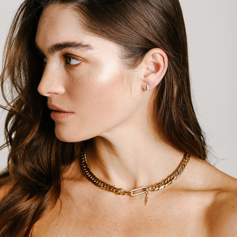 Model is wearing a mini clear huggies silver and the PANAREA NECKLACE which is a 17" 18K gold plated stainless steel chunky chain with an 18k gold plated lightning charm and Zirconia charm. 