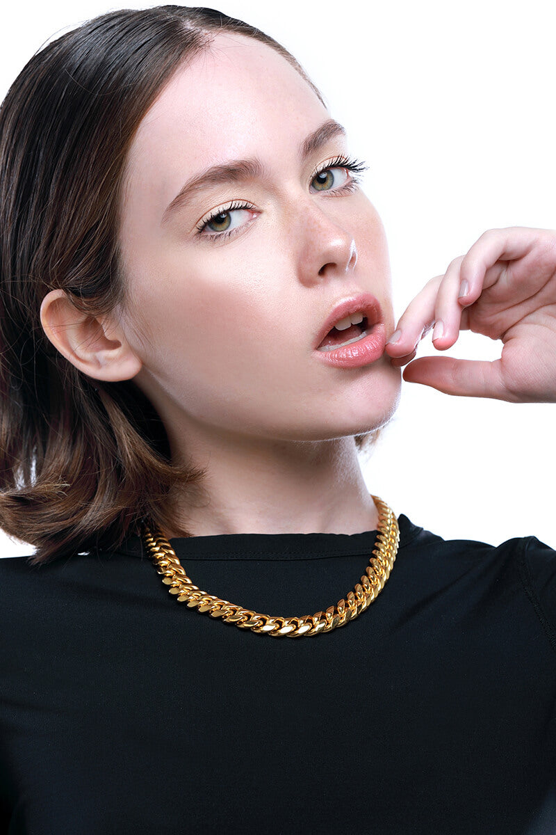 Model wearing a black top accessorized with the Palma Necklace which is a thick chain made of Gold plated Stainless steel with box lock. 