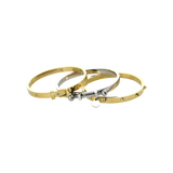 The BALANCE BRACELET STACK, a stylish three-piece bangle set featuring a mix of gold and silver tones with intricate details like a buckle clasp and studded accents. Perfect for adding a touch of edgy elegance to any outfit.