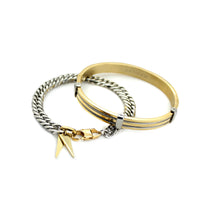 The Iron Stack, a two-piece gold and silver bracelet stack featuring a gold bangle with textured detailing and a silver chain bracelet with a geometric charm.