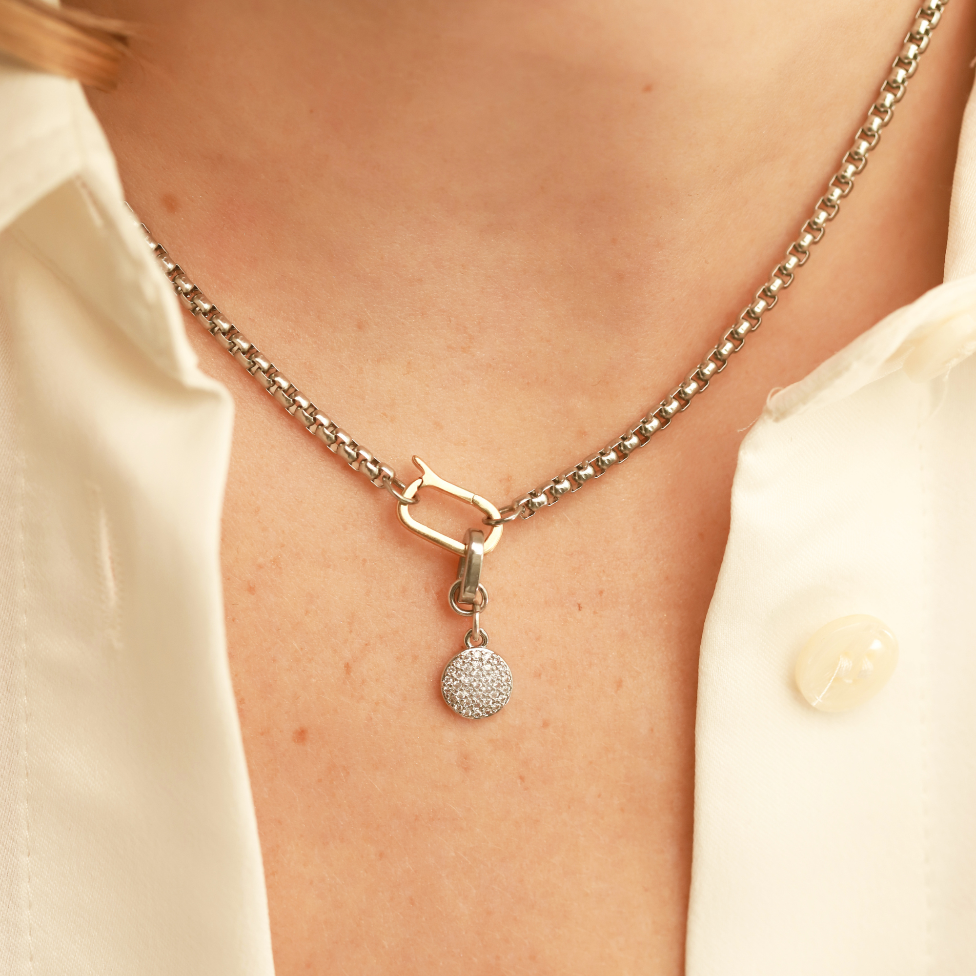 Model wearing a can opener necklace with the Dot Link Charm, which is a circle shaped diamond encrusted charm. ||| SILVER
