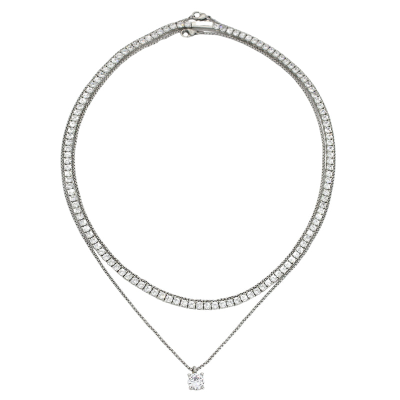 The TENNIS NECKLACE SET which includes three layered necklaces. One is a 1mm wide, Stainless steel Rhodium plated chain, a Rhodium-plated brass/cubic zirconia tennis necklace and 18" necklace with a Solitaire 1 ct zirconia pendant. 